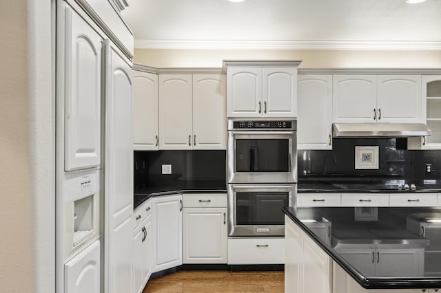 2758 N Highland Ave, Fresno, CA 93737 - kitchen with double oven, under cabinet range hood, crown molding, dark countertops, and tasteful backsplash