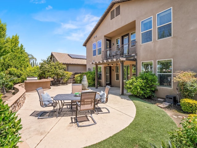 view of patio / terrace featuring a balcony, fence, exterior kitchen, and outdoor dining space