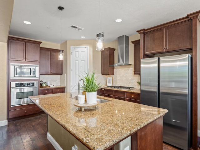 kitchen with stainless steel appliances, wall chimney range hood, light stone counters, dark wood finished floors, and recessed lighting