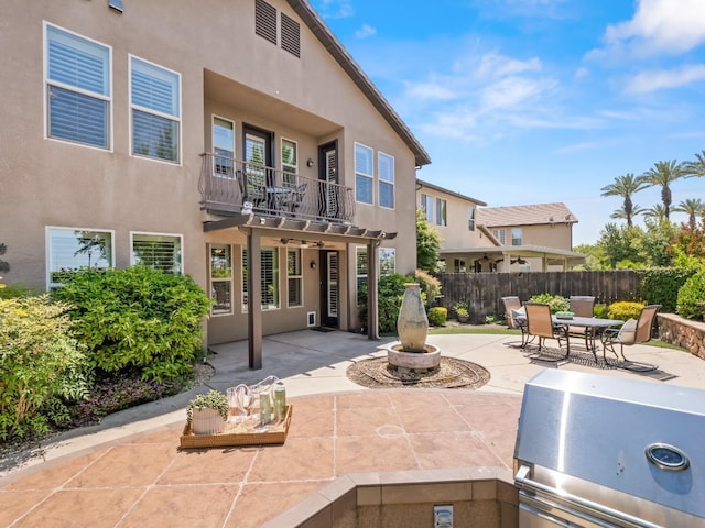 back of property with a patio area, stucco siding, fence, and a balcony