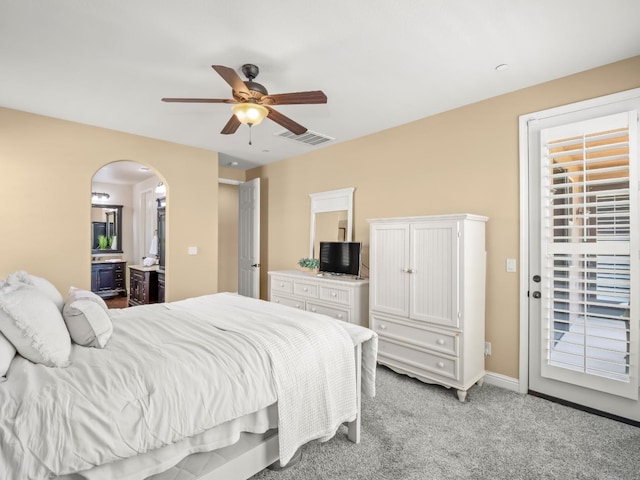 bedroom featuring access to outside, light colored carpet, arched walkways, a ceiling fan, and ensuite bath