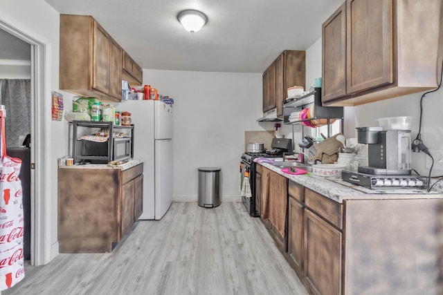 1197 Pucheu St, Mendota, CA 93640 - kitchen with black range with gas cooktop, freestanding refrigerator, light wood-style flooring, under cabinet range hood, and a sink