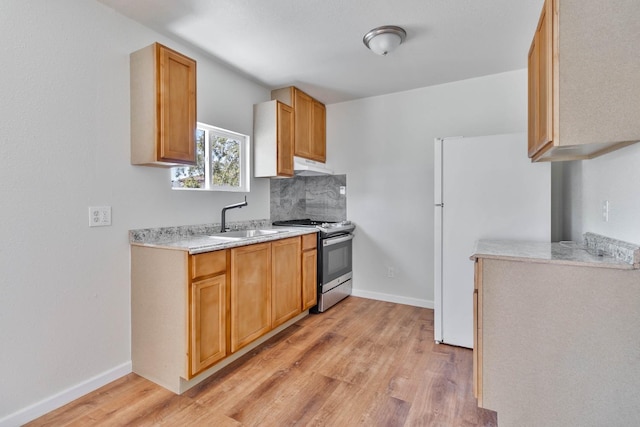 1197 Pucheu St, Mendota, CA 93640 - kitchen with gas range, freestanding refrigerator, under cabinet range hood, a sink, and light countertops