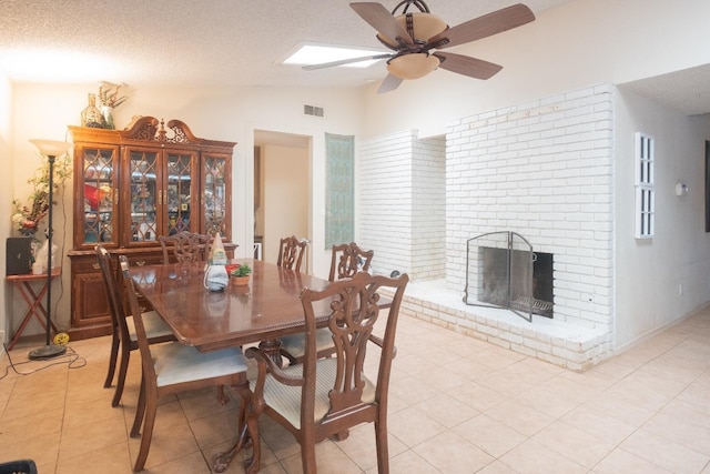 dining room featuring lofted ceiling, a ceiling fan, light tile patterned floors, a fireplace, and a textured ceiling