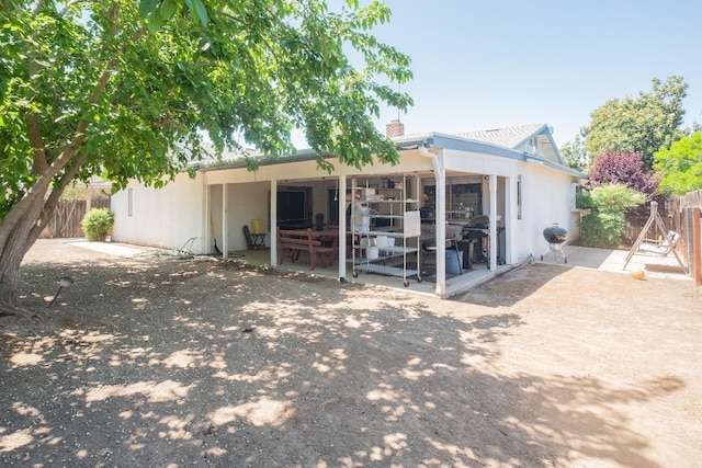 rear view of house with a patio, fence, a chimney, and stucco siding