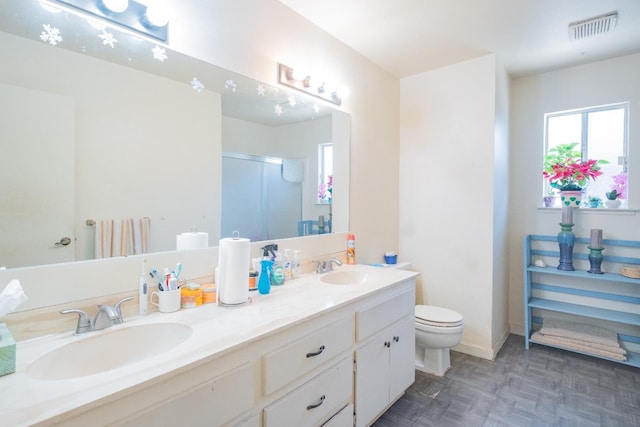 full bath featuring a stall shower, double vanity, toilet, and baseboards