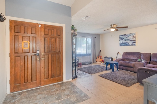 living area featuring a ceiling fan, tile patterned flooring, and a textured ceiling