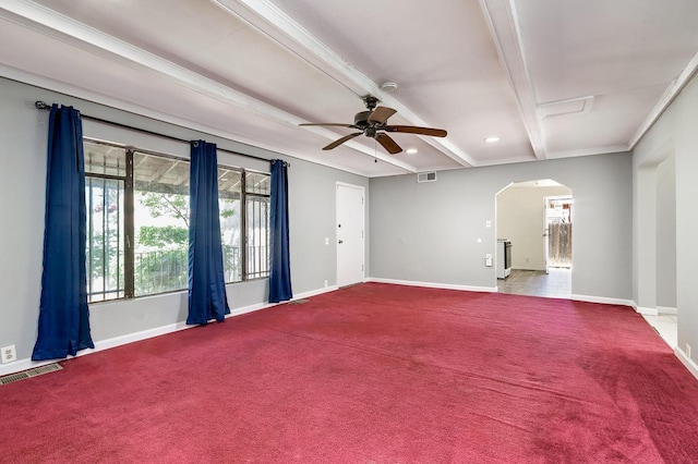 empty room featuring arched walkways, beam ceiling, baseboards, a ceiling fan, and carpet flooring