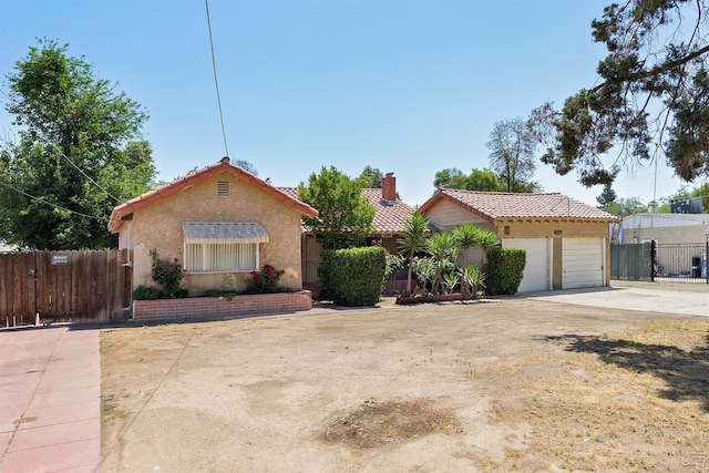view of front facade featuring a tiled roof, a chimney, fence, and stucco siding