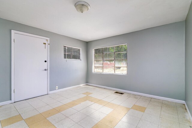 empty room with baseboards and light tile patterned floors