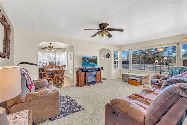 living room with arched walkways, a ceiling fan, and carpet floors