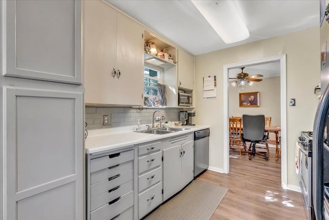 kitchen featuring a sink, appliances with stainless steel finishes, backsplash, light wood-style floors, and light countertops