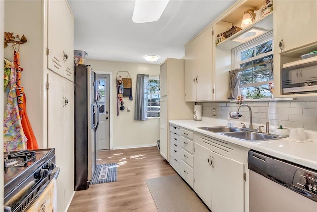kitchen featuring stainless steel appliances, a sink, tasteful backsplash, light countertops, and baseboards