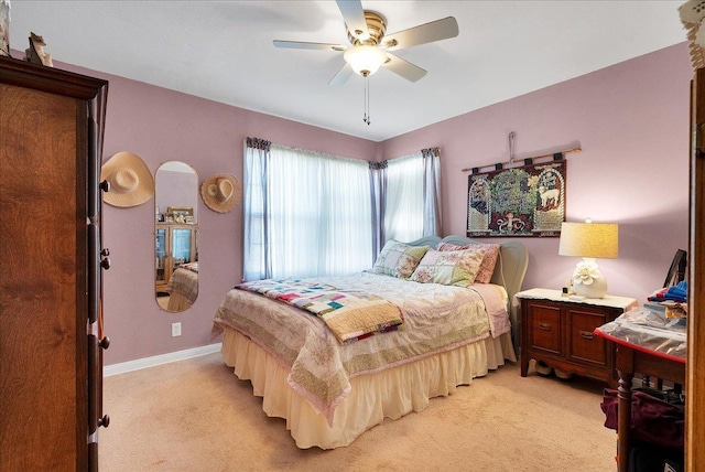 bedroom with light colored carpet, ceiling fan, and baseboards