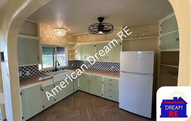 kitchen featuring freestanding refrigerator, open shelves, arched walkways, a ceiling fan, and backsplash