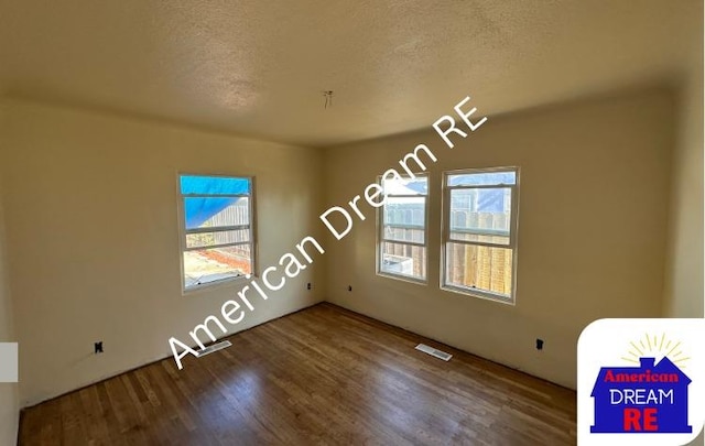 spare room featuring a textured ceiling and wood finished floors