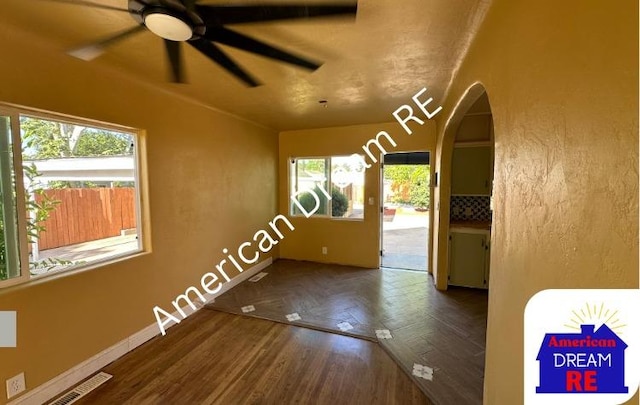 unfurnished room featuring arched walkways, plenty of natural light, ceiling fan, and baseboards