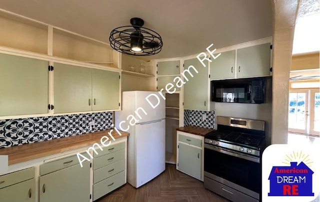 kitchen featuring stainless steel range with gas cooktop, black microwave, freestanding refrigerator, and decorative backsplash