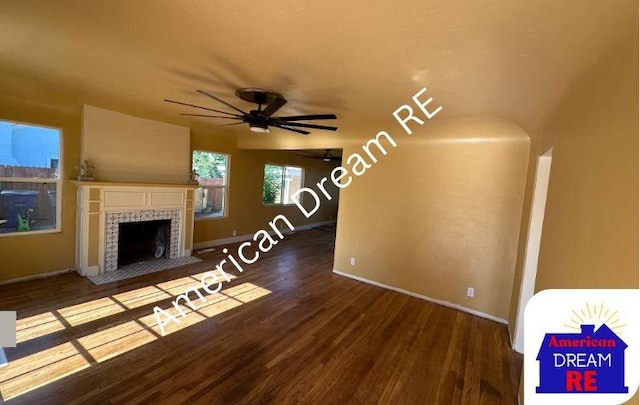 unfurnished living room with wood finished floors, ceiling fan, baseboards, and a tile fireplace