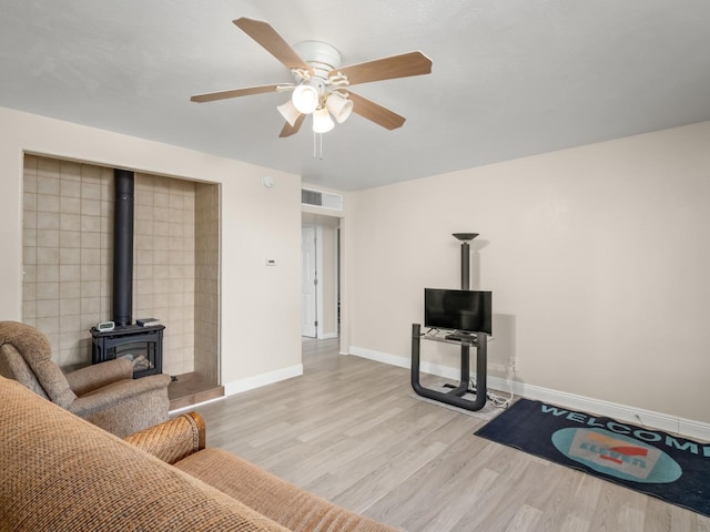 4740 E Princeton Ave, Fresno, CA 93703 - living room featuring a wood stove, baseboards, light wood-type flooring, and ceiling fan