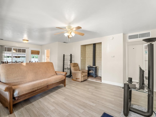 4740 E Princeton Ave, Fresno, CA 93703 - living room featuring a wood stove, ceiling fan, light wood-style floors, and baseboards