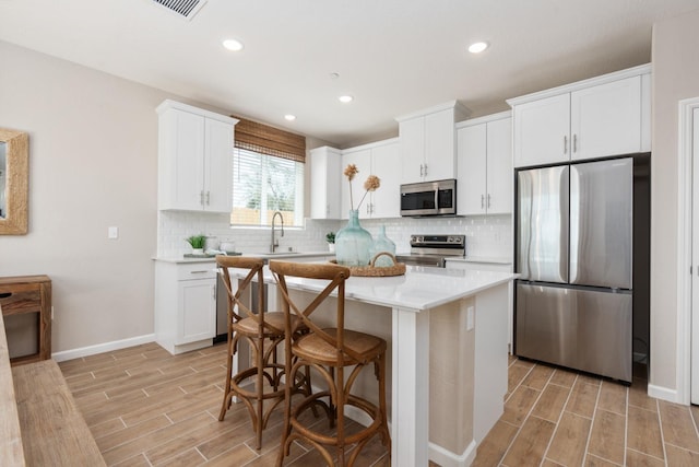 kitchen featuring appliances with stainless steel finishes, wood tiled floors, light countertops, decorative backsplash, and recessed lighting