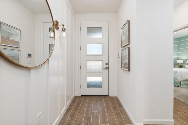 doorway with wood finished floors and baseboards