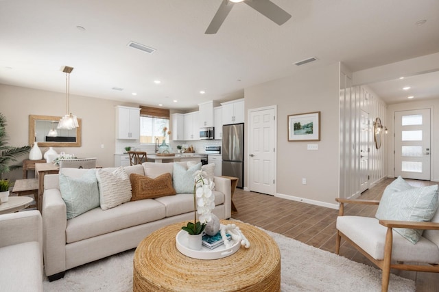 living room with light wood-style floors, a ceiling fan, recessed lighting, and baseboards