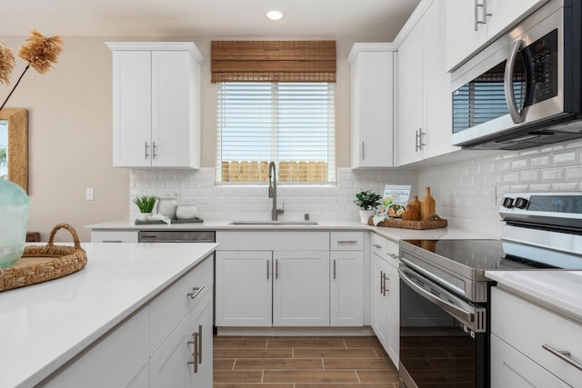 kitchen featuring stainless steel appliances, a sink, recessed lighting, light countertops, and white cabinetry