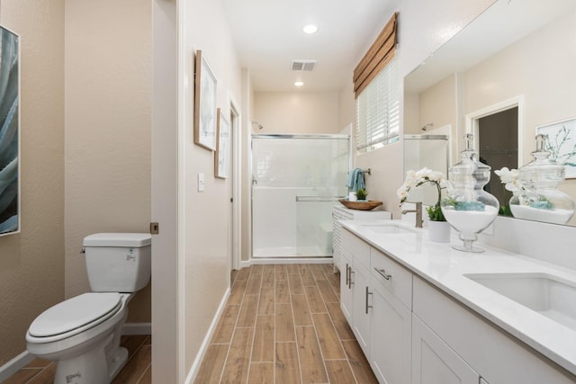 bathroom featuring a shower stall, toilet, wood finished floors, double vanity, and recessed lighting