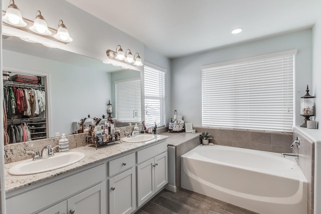3877 Griffith Ave, Clovis, CA 93619 - full bathroom featuring wood finished floors, a garden tub, double vanity, a walk in closet, and recessed lighting