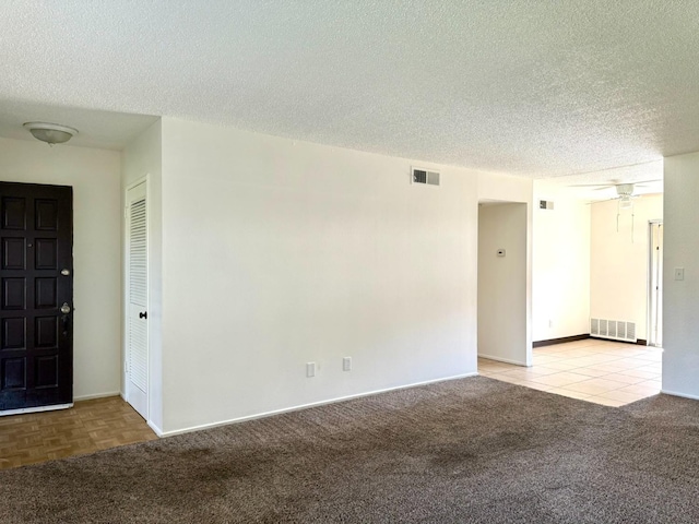 carpeted empty room with a textured ceiling, baseboards, and a ceiling fan