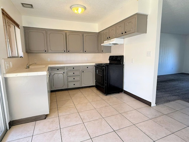 kitchen featuring electric range, gray cabinets, under cabinet range hood, a sink, and tasteful backsplash