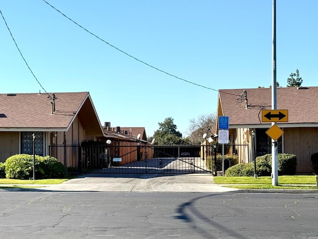 view of asphalt road featuring traffic signs, a gate, and sidewalks
