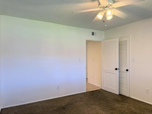 unfurnished bedroom featuring carpet floors, a closet, a textured ceiling, and ceiling fan