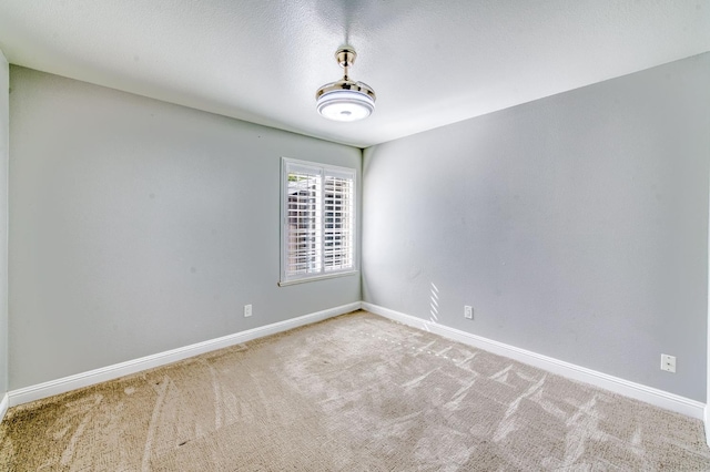 carpeted spare room featuring baseboards