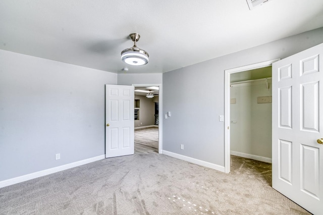 unfurnished bedroom with a spacious closet, carpet flooring, baseboards, and a closet