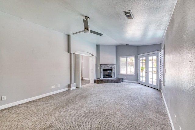 unfurnished living room featuring french doors, a ceiling fan, baseboards, a textured ceiling, and a textured wall