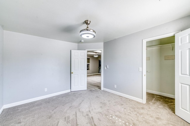 unfurnished bedroom featuring a spacious closet, carpet, and baseboards