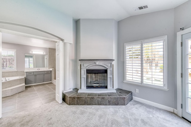unfurnished living room featuring a tiled fireplace, vaulted ceiling, a sink, baseboards, and carpet