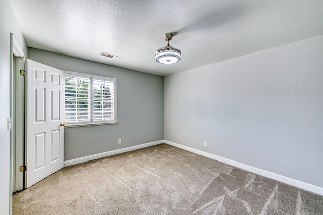 carpeted spare room with baseboards and a textured ceiling