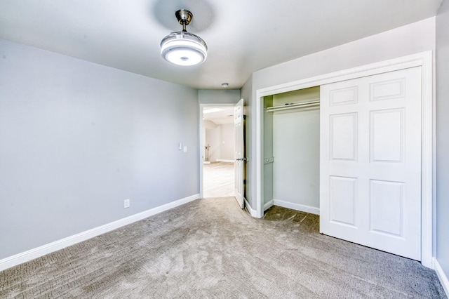 unfurnished bedroom with carpet, a closet, and baseboards