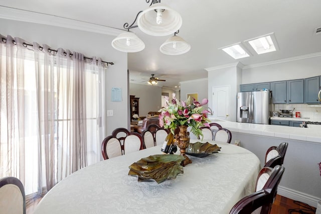 dining area with crown molding, a ceiling fan, and a skylight