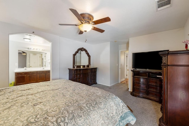 bedroom featuring carpet floors, baseboards, ensuite bathroom, ceiling fan, and a sink
