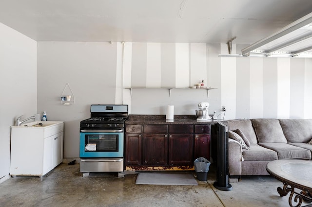 kitchen featuring stainless steel range with gas stovetop, concrete floors, open floor plan, and dark countertops