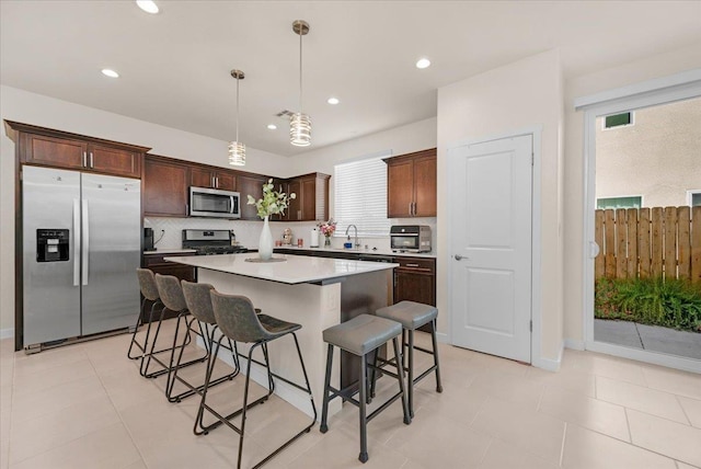 841 Corazon Ave, Clovis, CA 93619 - kitchen featuring appliances with stainless steel finishes, a kitchen bar, a center island, tasteful backsplash, and decorative light fixtures