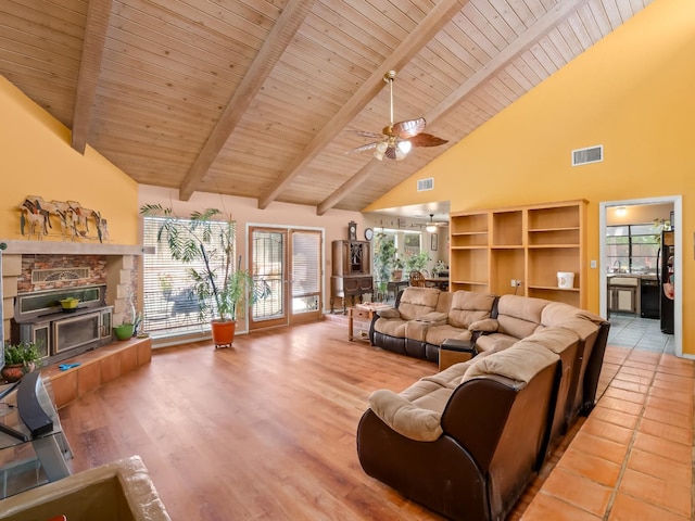living area featuring high vaulted ceiling, wood ceiling, beam ceiling, a ceiling fan, and a fireplace