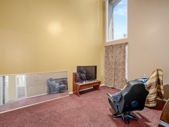 sitting room with carpet flooring, a towering ceiling, and baseboards