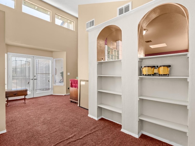carpeted foyer featuring french doors, a high ceiling, and baseboards