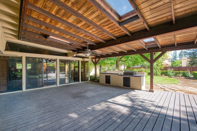 wooden terrace with an outdoor kitchen, fence, a ceiling fan, and a grill